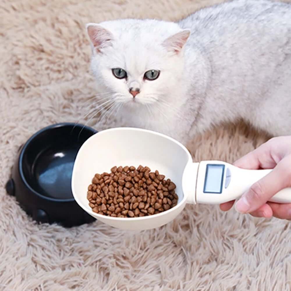 Smart Pet Food Measuring Scoop filled with pet food, with a cat in the background.